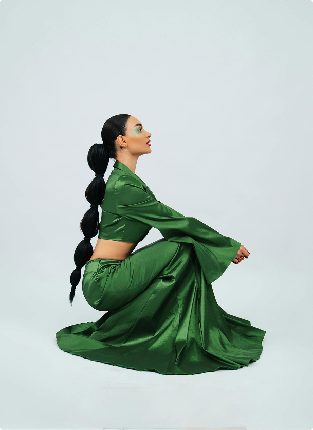 Model wearing an emerald green satin co-ord set in a seated pose
